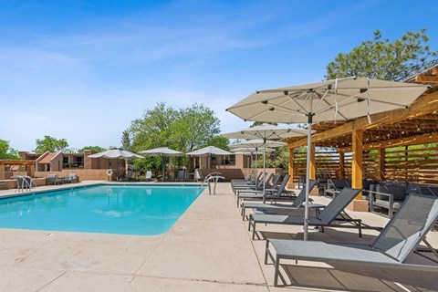 the resort style pool is surrounded by lounge chairs and umbrellas at Acacia Gardens, Albuquerque, New Mexico